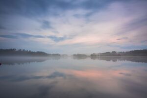 A lake at sunrise is covered in mysterious looking fog.