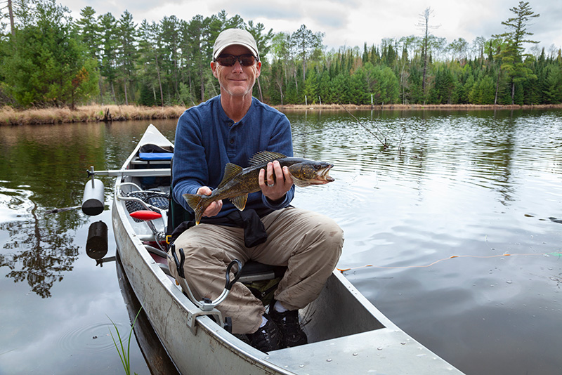 Smiling fisherman proudly displays a freshly caught walleye in Minnesota.
